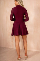 Woman wearing a burgundy dress against a beige background